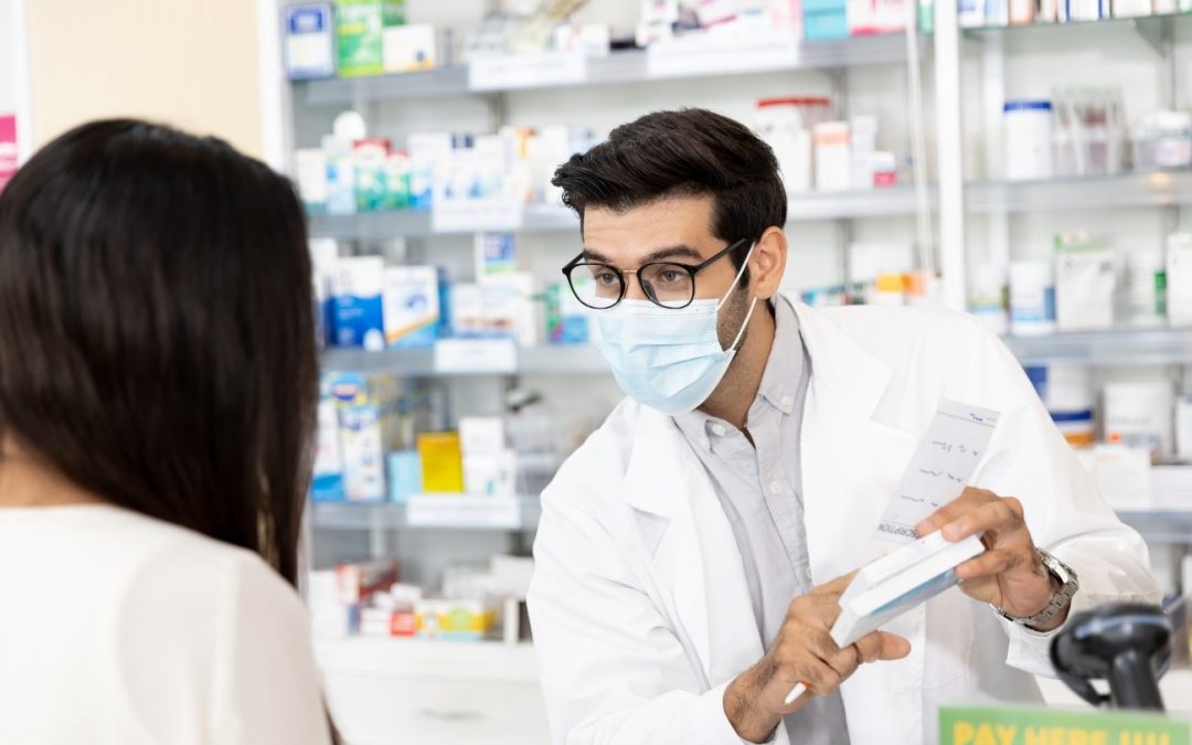 Un farmaceutico en un mostrador de una farmacia atendiendo.